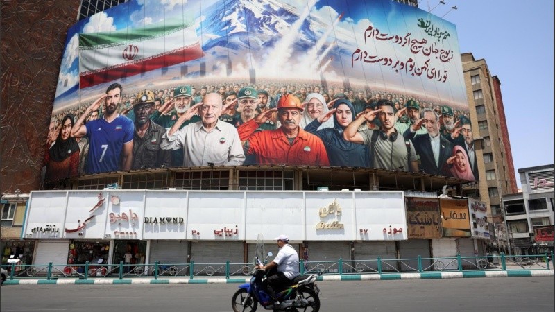 Cartel con varios iraníes, incluyendo militares y al ministro de Asuntos Exteriores iraní, Abbas Araghchi (3-D), saludando y con un mensaje que dice 