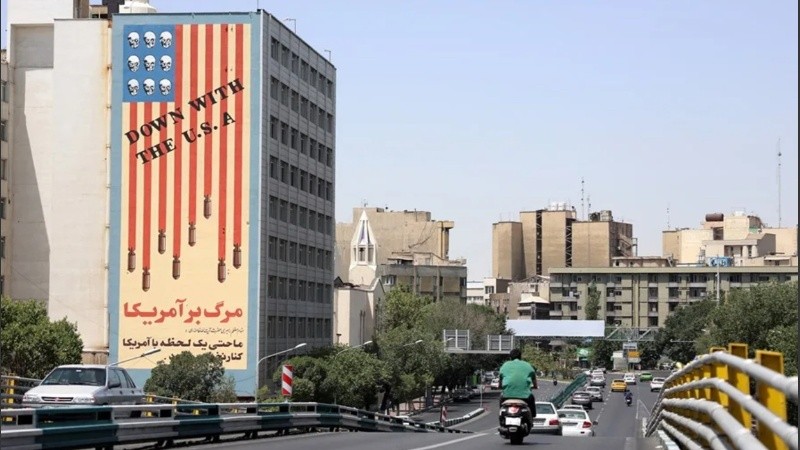 Coches circulan junto a un edificio que muestra un mural contra Estados Unidos en Teherán, Irán.